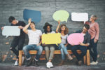 Shot of a diverse group of people holding up speech bubbles outside.