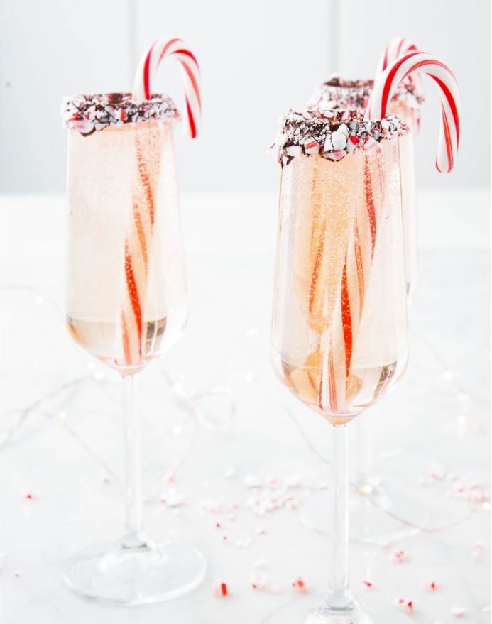 Filled champagne flutes with candy canes in them and rimmed with chocolate and crushed candy canes.