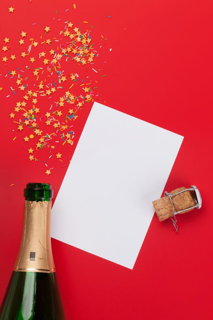 Champagne bottle, blank card and sweets holiday template. Christmas, Birthday or Valentines'day backdrop. Top view with space for your greetings