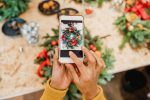 Point of view shot of a florist taking a picture of a wreath on a smartphone for social media.