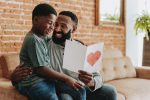 Son handing greeting card to father