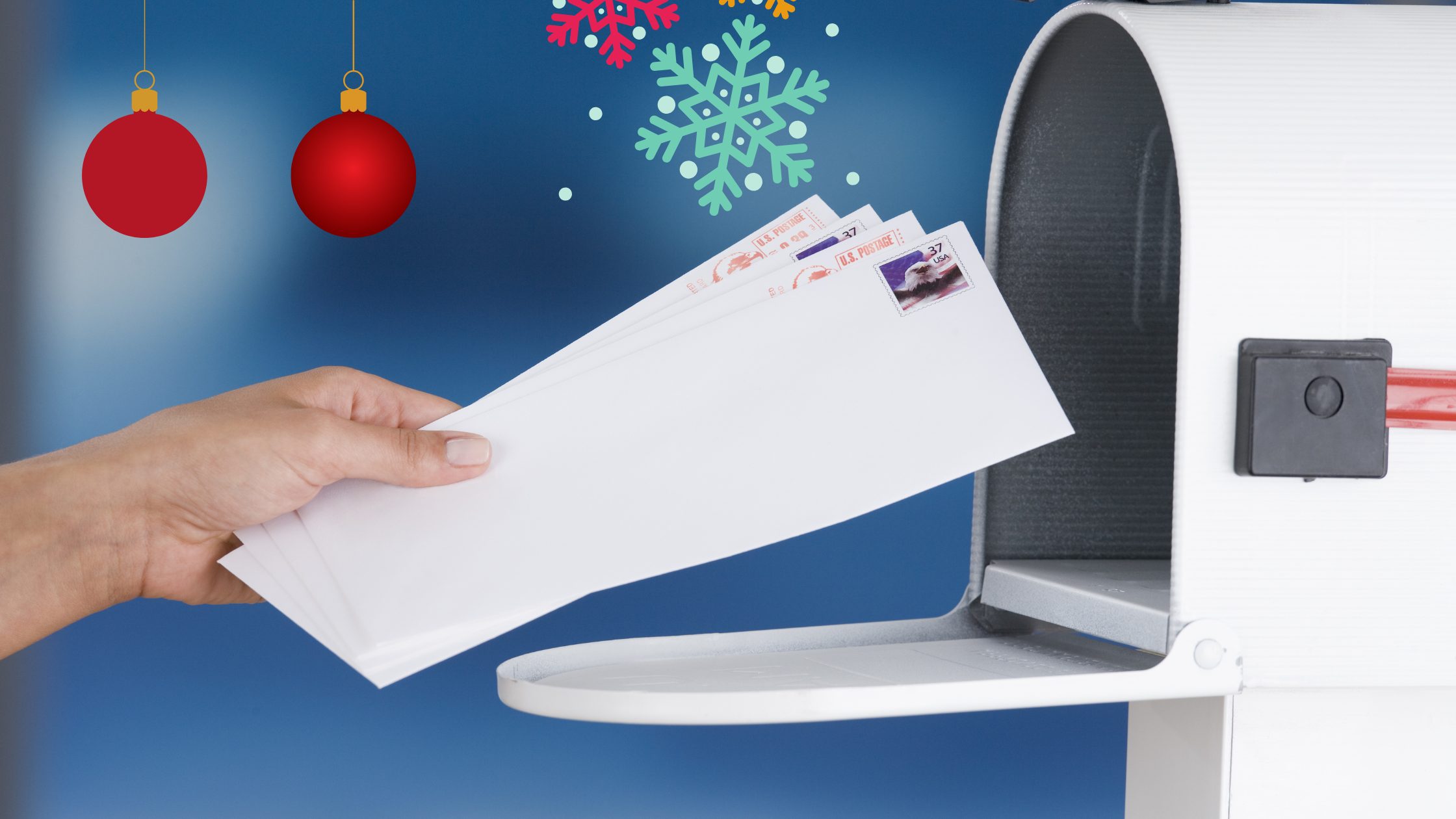 Someone dropping holiday mail into the mailbox.
