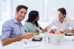 People around a table at an office eating sushi.