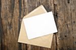 A greeting card on top of a gold envelope on a wooden background.