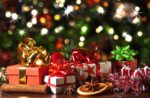 An array of holiday gifts with a Christmas tree background.