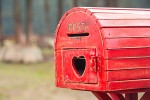 A red mailbox with a heart-shaped cutout in the door.