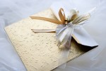 A fancy wedding invitation with gold accents and a gold and white bow.