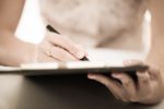 A woman writing on a clipboard.