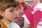 A boy holding a homemade paper valentine.