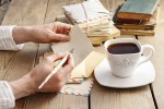 A woman writing a note with a fountain pen and a coffee near by.