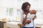 A woman holding a baby in your home.