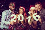 Four people celebrating the new year holding individual numbers that spell 2016.